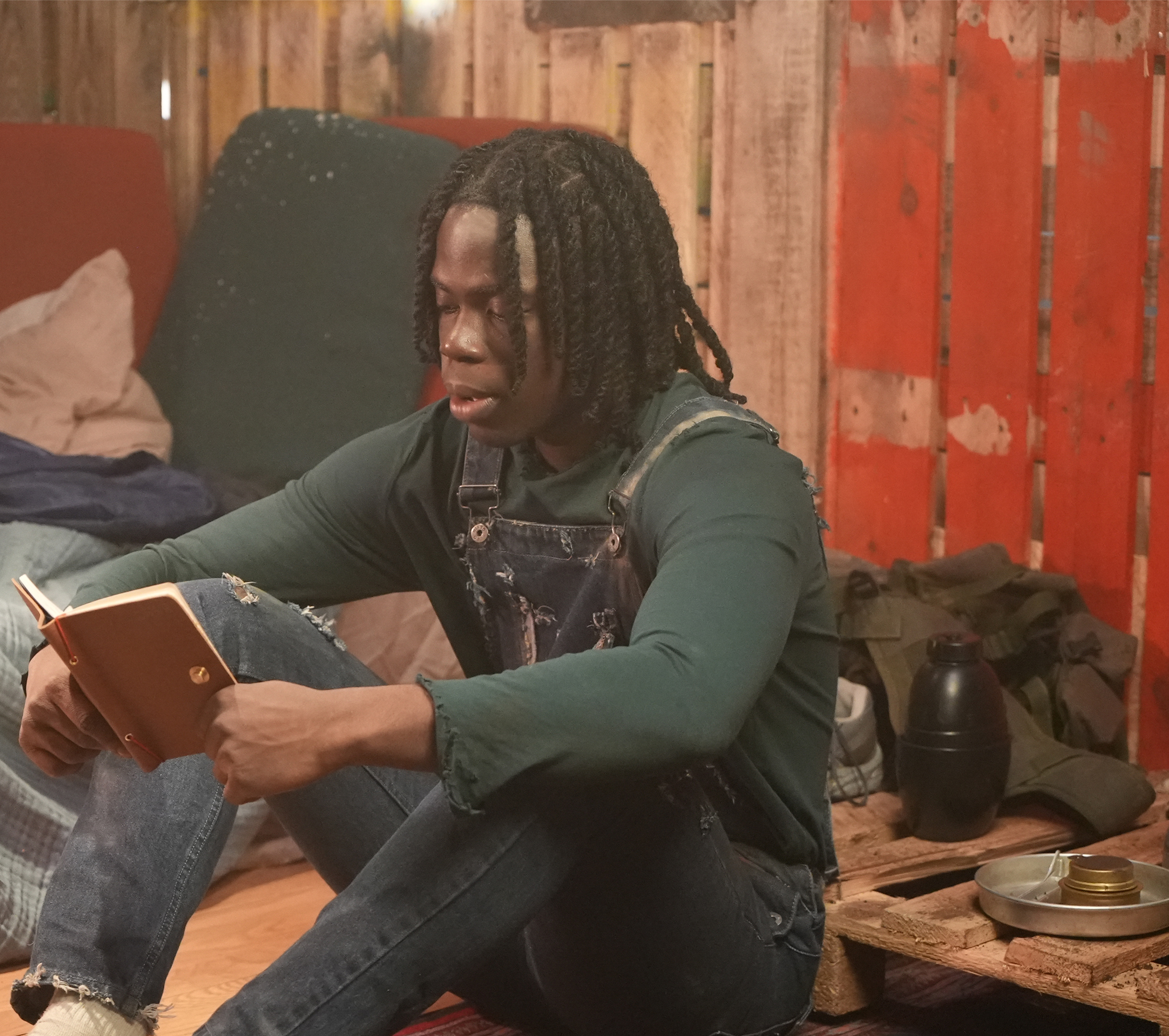 Boy sitting on floor with red book in his hand on film set.