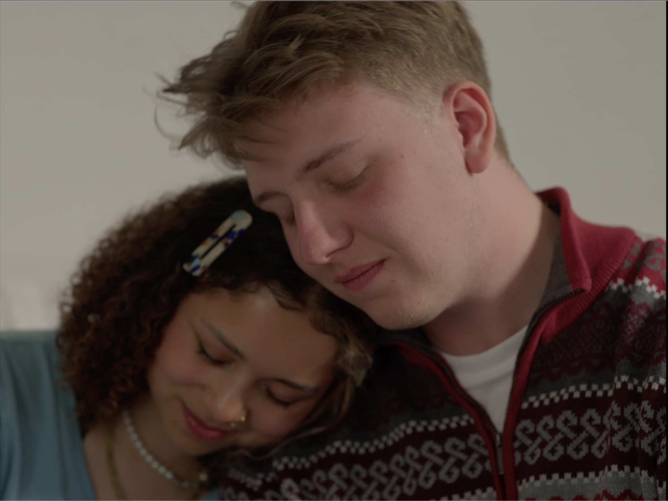A man and woman sit side by side, heads and shoulders together